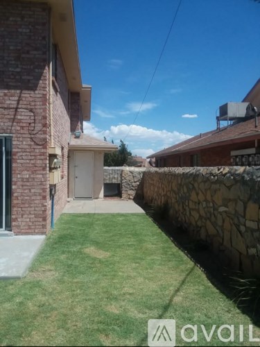 A house with a green lawn and a stone wall.