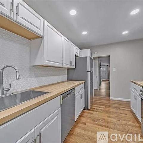 A kitchen with white cabinets and wooden countertops.