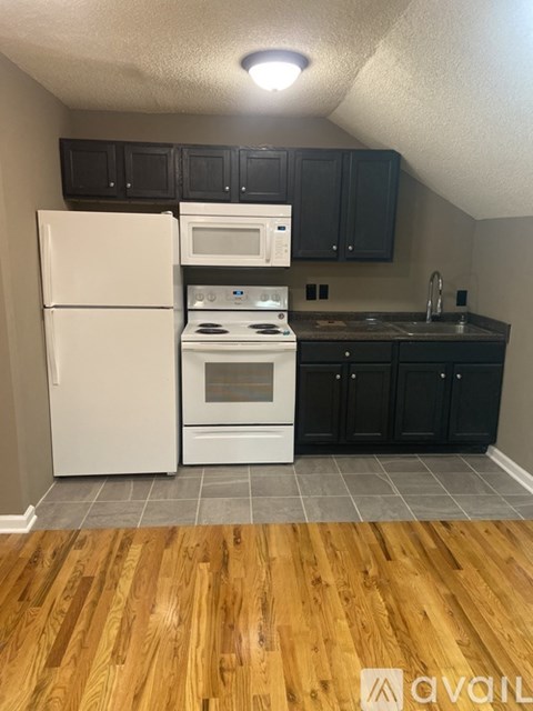 A kitchen with a white fridge and black cabinets.