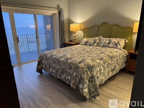 A bedroom with a large bed and a balcony overlooking the ocean.
