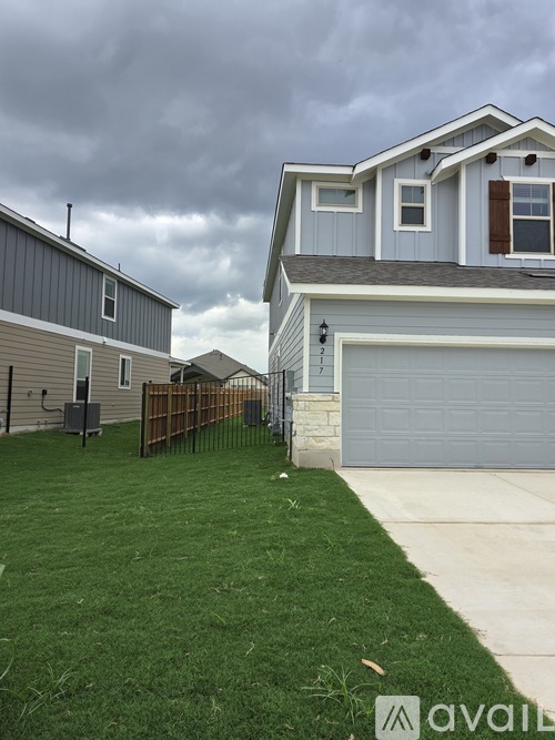 A house with a grey garage door and a green lawn.