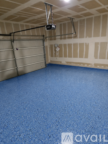 A room with a blue floor and a grey garage door.