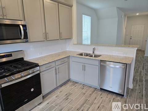 A kitchen with a black stove top oven and a white sink.