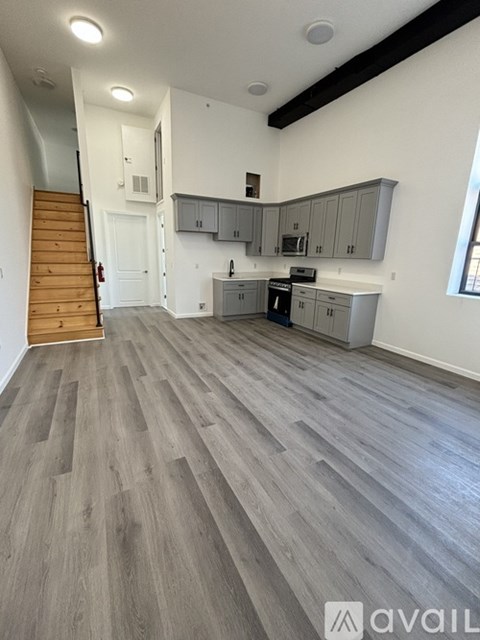 A kitchen with wooden floors and a staircase on the left side.