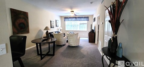 A living room with a black chair and a table with a vase of flowers on it.
