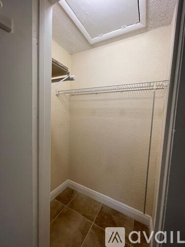 A small, empty walk-in closet with a metal rack and a tiled floor.