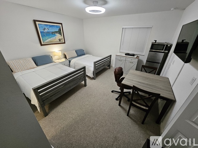 A bedroom with a blue bed and a painting on the wall.