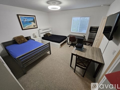 A bedroom with a blue bed and a painting on the wall.