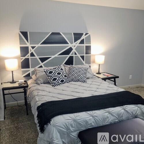 A bedroom with a large bed and two lamps.
