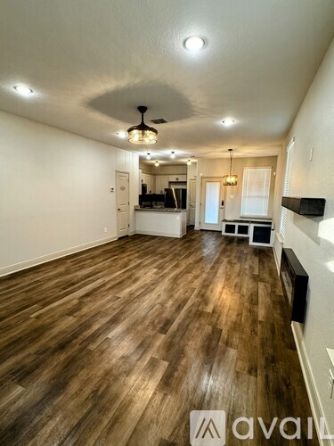 A spacious room with wooden flooring and a ceiling fan.