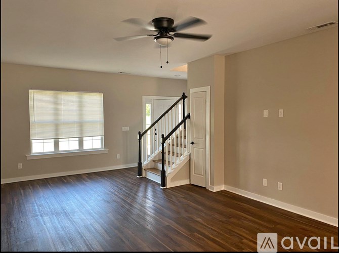 A spacious room with a staircase leading to the second floor.