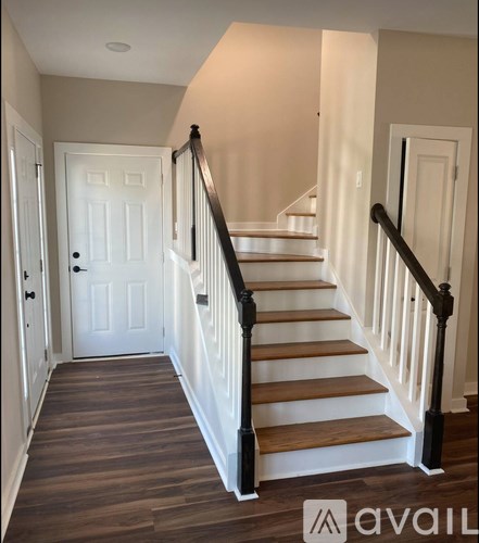 A staircase with a wooden handrail and steps leading to a door at the top.