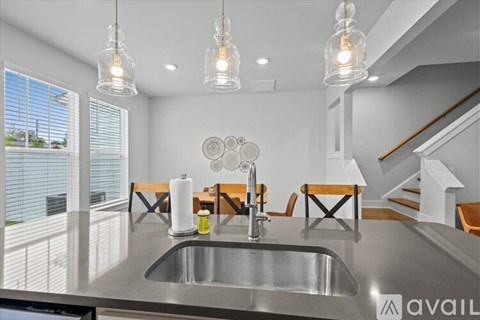 A modern kitchen with a stainless steel sink and pendant lights.