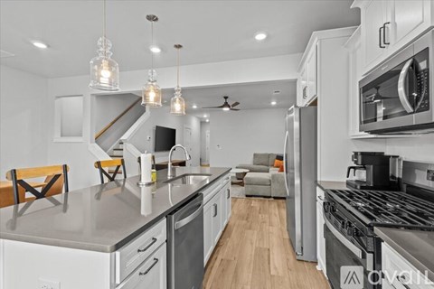 A modern kitchen with stainless steel appliances and wooden flooring.