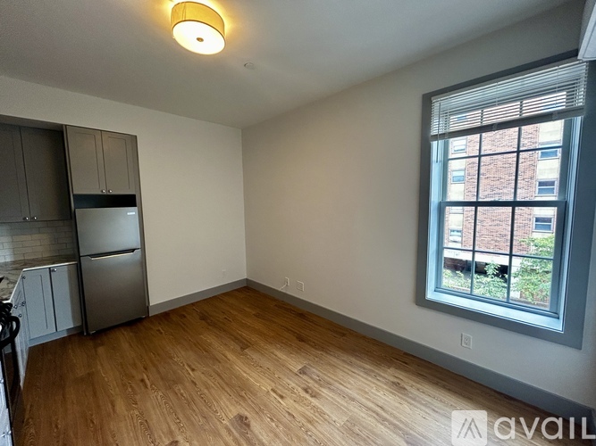 A kitchen with a refrigerator and wooden floors.