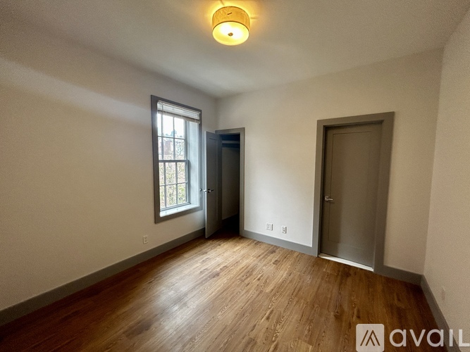 A room with wooden floors and a window on the left side.