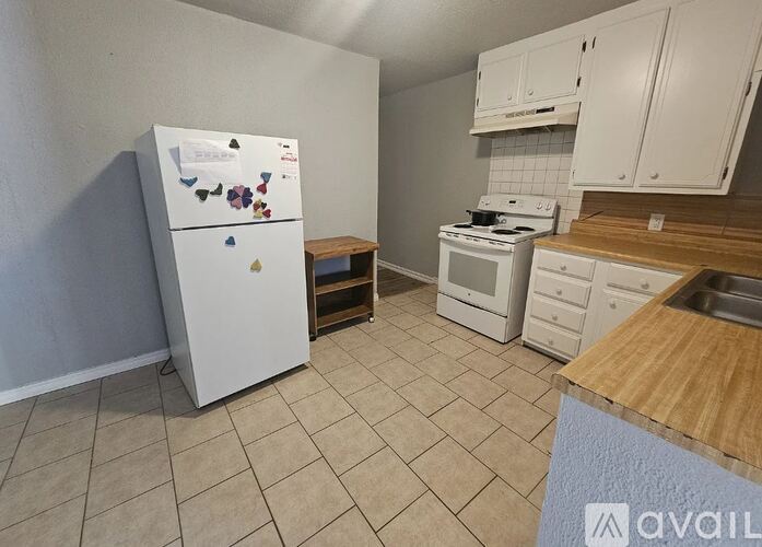 A kitchen with white appliances and wooden countertops.