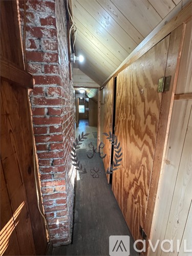 A long hallway with wooden walls and a brick pillar on the left.