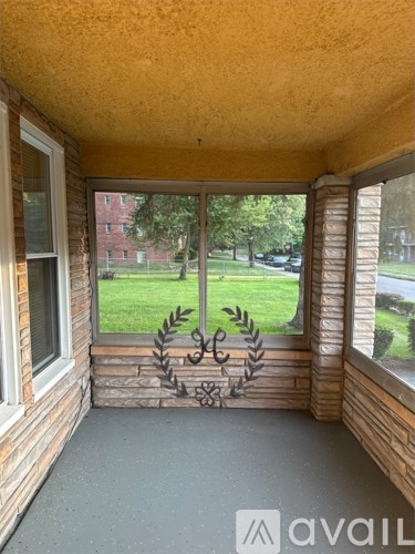 A balcony with a view of a green lawn and trees.