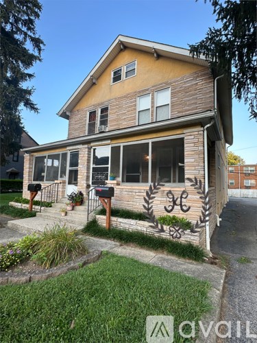 A house with a lawn in front and mailboxes on the side.