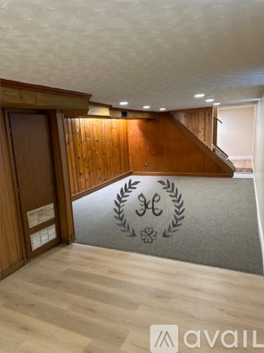 A hallway with a wooden floor and a staircase.