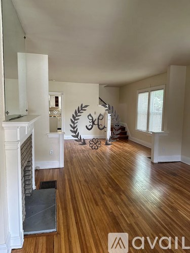 A room with wooden floors and a fireplace with a mirror above it.