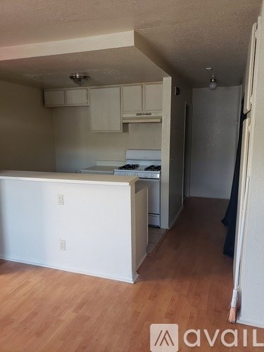 A kitchen with white cabinets and a wooden floor.