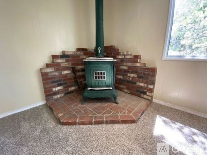 A green wood stove in a room with a brick base.