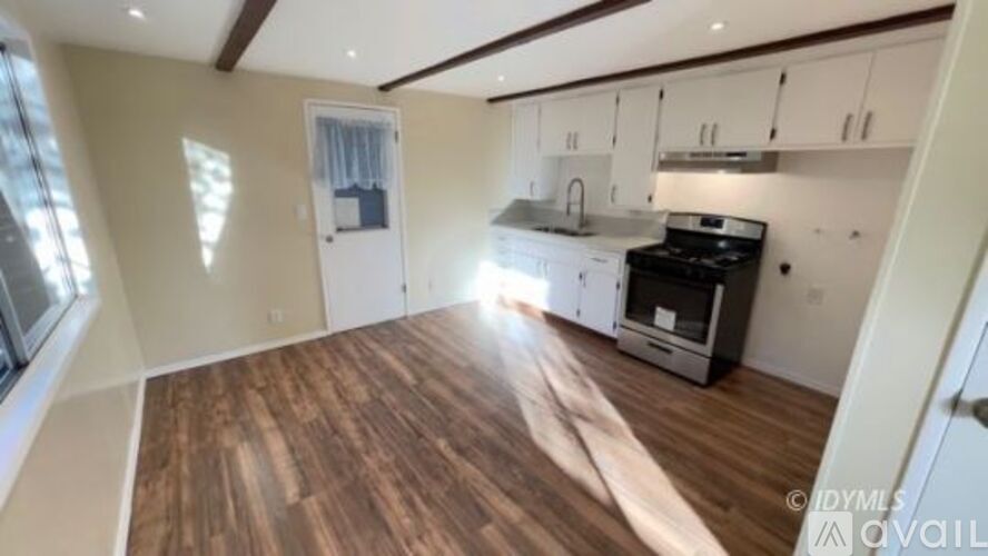 A kitchen with white cabinets and a wooden floor.