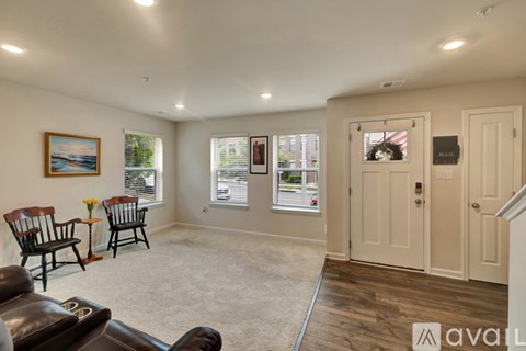 A living room with a brown leather couch, a painting, and a window with a view of the outside.