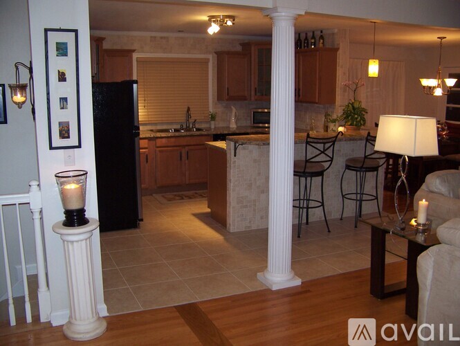 A kitchen with a black refrigerator and wooden cabinets.