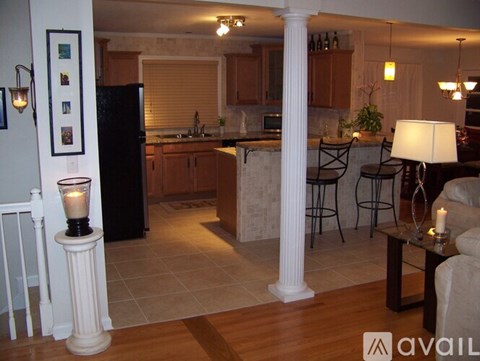A kitchen with a black refrigerator and wooden cabinets.