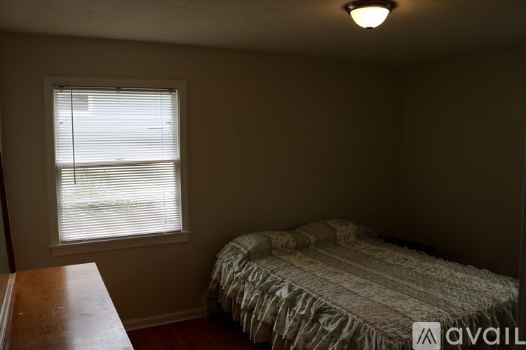 A bedroom with a bed and a window with blinds.