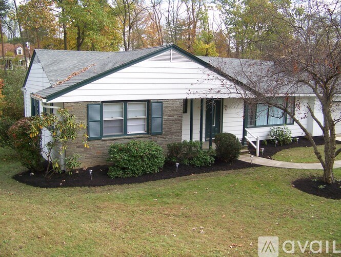 A house with a white siding and a grey roof with a small front yard.