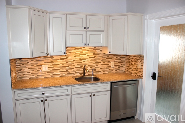 A kitchen with white cabinets and a stone backsplash.