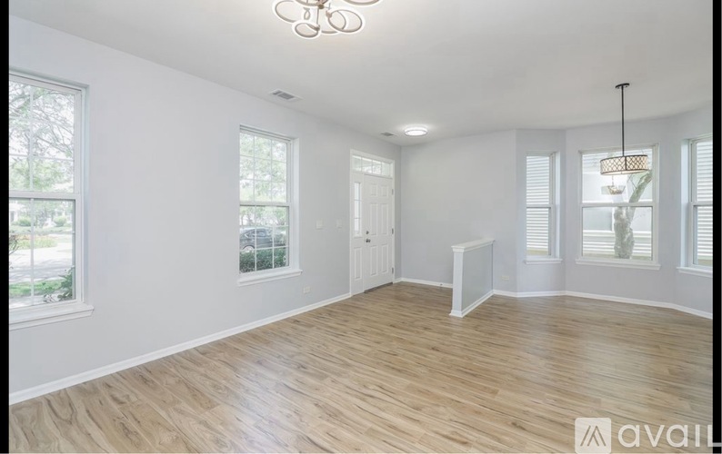 A room with wooden flooring and white walls, with a chandelier hanging from the ceiling.