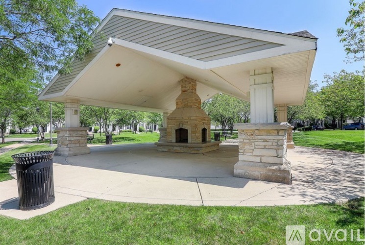 A gazebo-like structure with a white roof and stone pillars is surrounded by a grassy area.