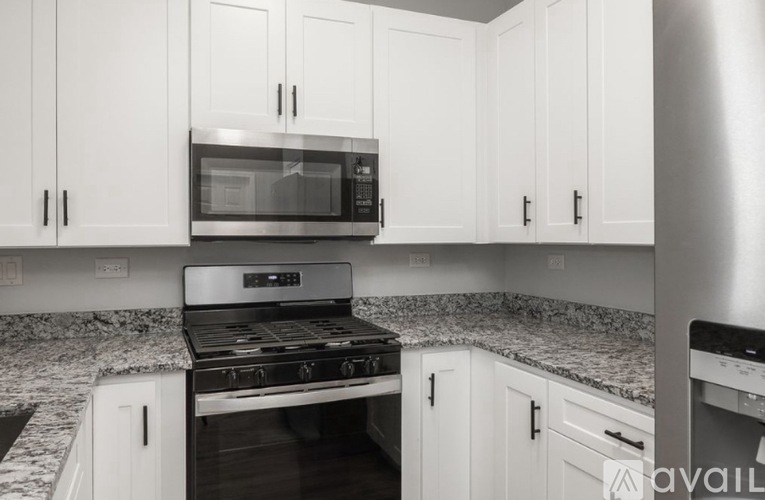 A kitchen with white cabinets and a granite countertop.