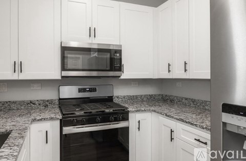 A kitchen with white cabinets and a granite countertop.