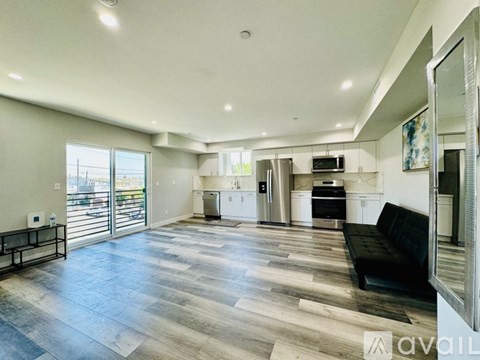 A spacious living room with a black couch and a television.