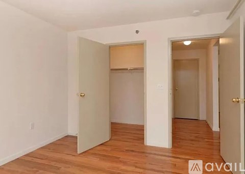 A room with wooden floors and white walls, with two doors and one of them is open.