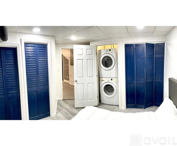 A white door is open to a hallway with a washing machine in the background.