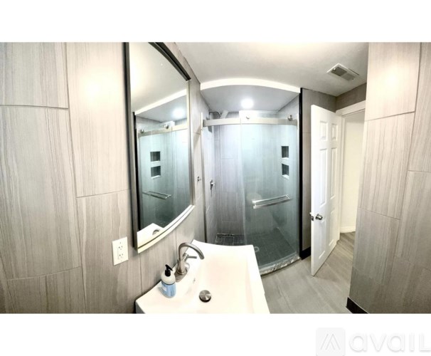 A bathroom with a sink, mirror, and shower.