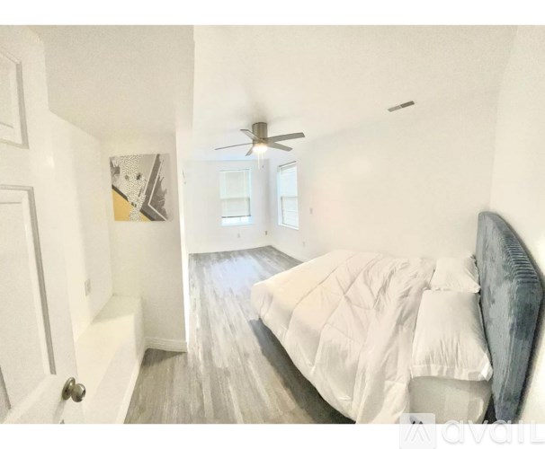 A bedroom with a bed, a ceiling fan, and a door.