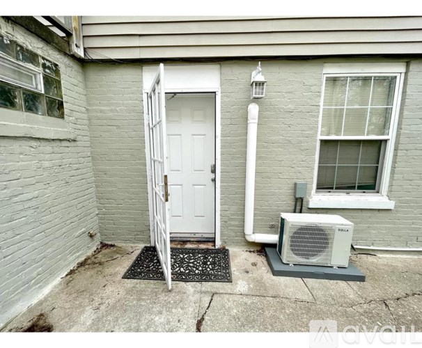 A white door is open to a small room with a window and a fan.