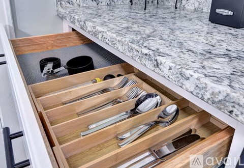 A drawer full of silverware is open in a kitchen.