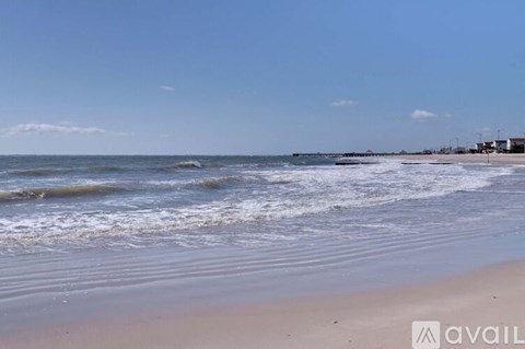 A beach with waves coming in and a clear sky.