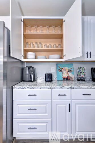 A kitchen with white cabinets and a marble countertop.