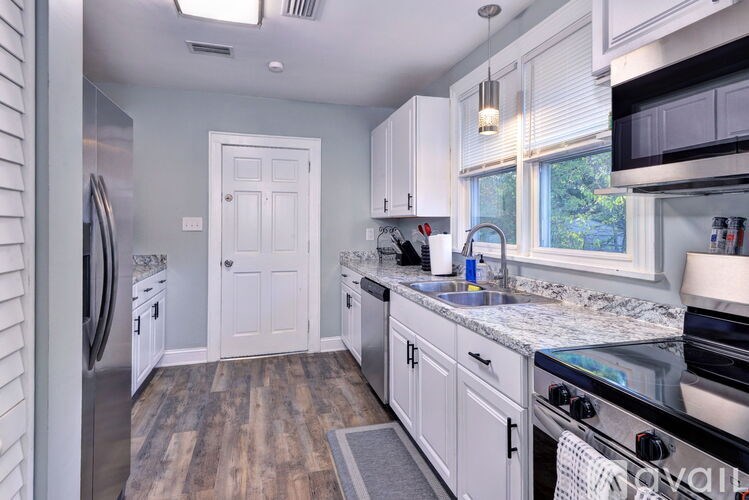 A kitchen with white cabinets and a wooden floor.