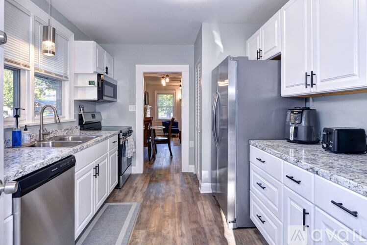 A kitchen with white cabinets and a marble countertop.